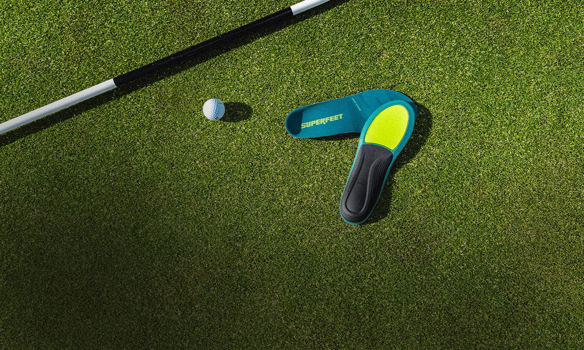 Superfeet Insoles against putting green with a golf ball & golf putter in the background. 