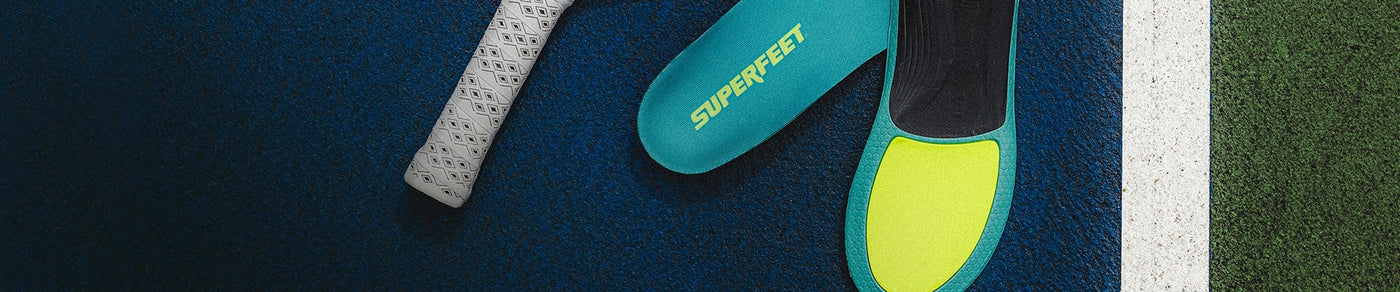 A close-up of Superfeet insoles on a blue court surface, 