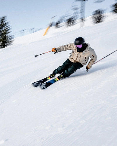 Person skiing down a snowy slope with trees in the background.