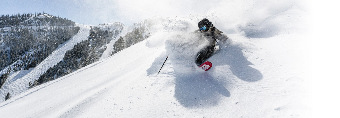 Person skiing down a snowy slope with mountains in the background. 