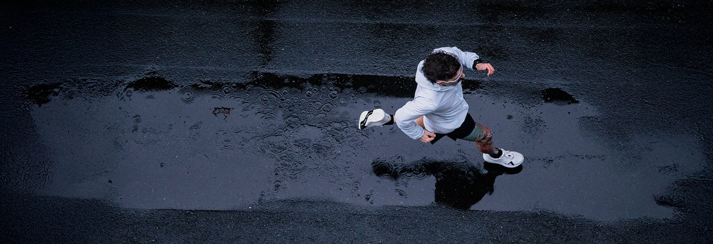 Birds eye view of a man running on wet pavement in the rain. 