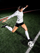 Soccer player in action on a field with a dark background. 