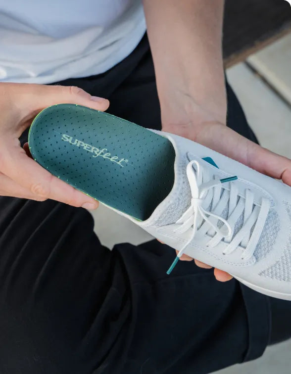 Person holding an athletic shoe with a Superfeet insole showing inside.