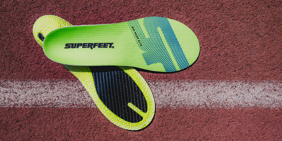 Superfeet bright green Run Pacer Elite insoles on a track background