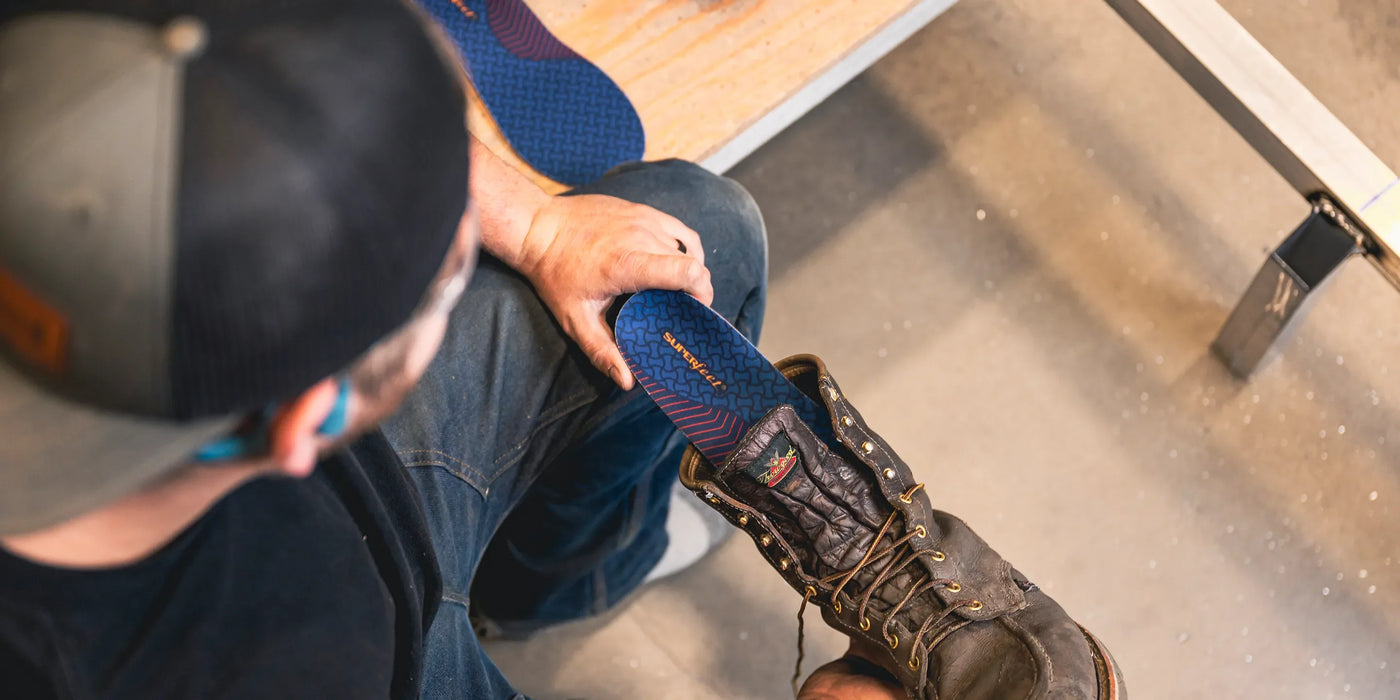 Man holding work boot and inserting a Superfeet work insole into his work boot.